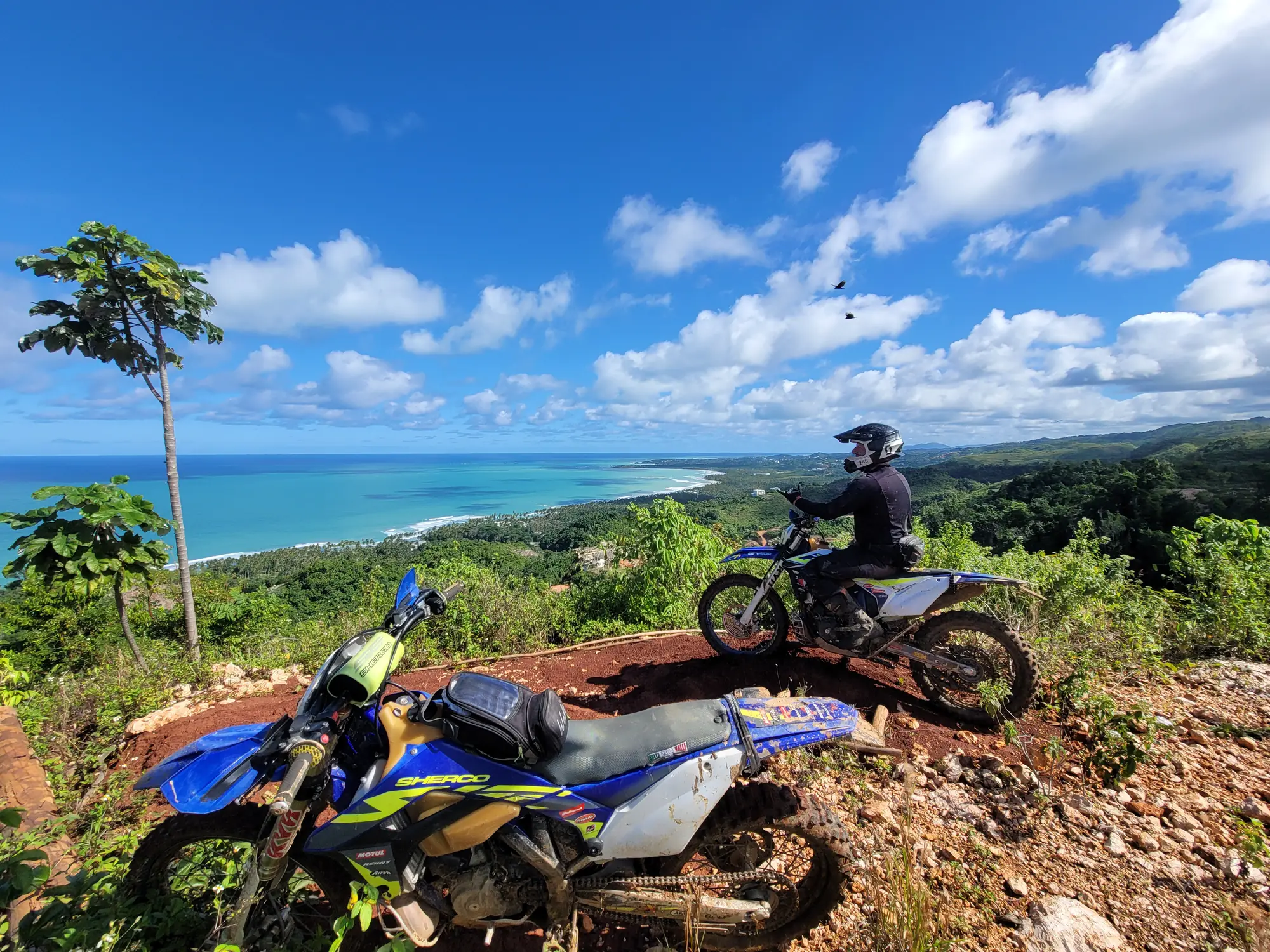 Riders on a red-dirt hilltop overlooking the Caribbean