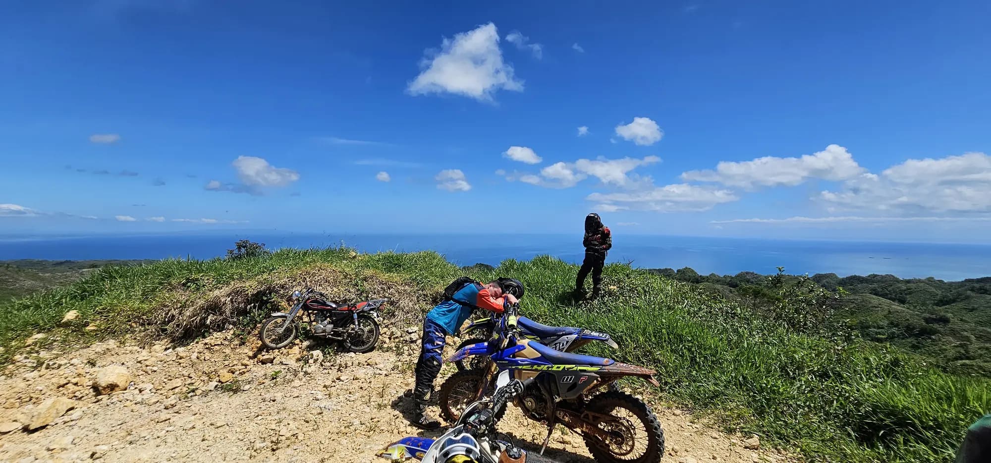 Rider and bike on a hilltop overlooking the sea