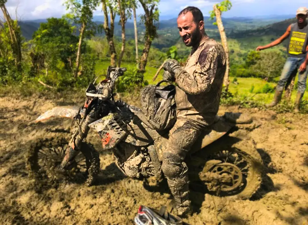 Mud-covered rider on a Sherco after a jungle section