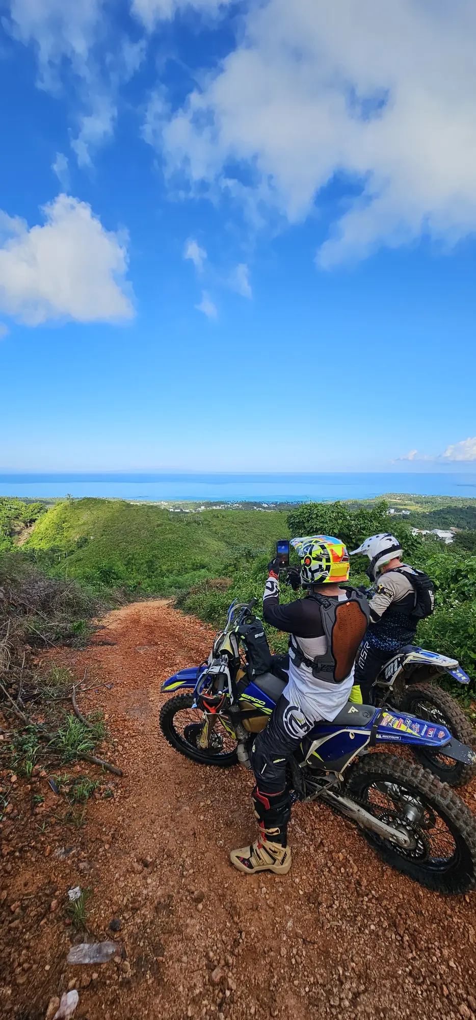 Riders on a red-dirt trail high above the coast